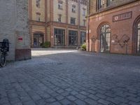 a brick courtyard outside of a large building with an archway at the end of it