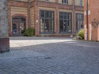 a brick courtyard outside of a large building with an archway at the end of it