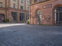 a brick courtyard outside of a large building with an archway at the end of it