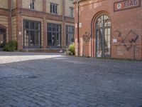 a brick courtyard outside of a large building with an archway at the end of it