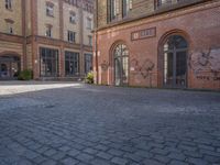 a brick courtyard outside of a large building with an archway at the end of it