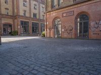 a brick courtyard outside of a large building with an archway at the end of it