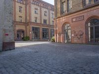 a brick courtyard outside of a large building with an archway at the end of it