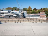 a concrete courtyard in front of a construction area, next to trees and large buildings