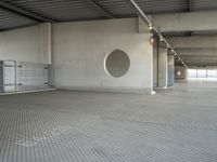 a parking garage that has cement floors and round holes on the wall and floor in front of door, ceiling