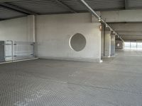 a parking garage that has cement floors and round holes on the wall and floor in front of door, ceiling