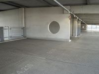 a parking garage that has cement floors and round holes on the wall and floor in front of door, ceiling