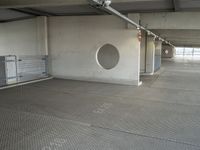 a parking garage that has cement floors and round holes on the wall and floor in front of door, ceiling