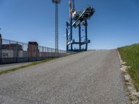 a small truck is in an empty lot next to a tall crane tower and some grass