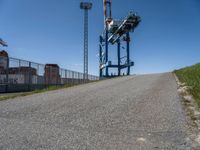 a small truck is in an empty lot next to a tall crane tower and some grass