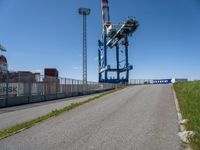 a small truck is in an empty lot next to a tall crane tower and some grass