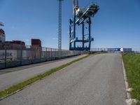 a small truck is in an empty lot next to a tall crane tower and some grass