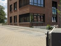 a building with a walkway that is next to trees and a sidewalk with people walking along it