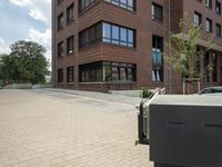 a building with a walkway that is next to trees and a sidewalk with people walking along it