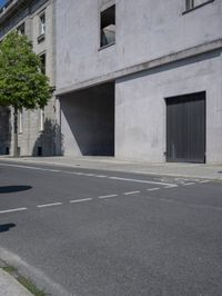 a man is riding a motorcycle in front of a building with a tree growing outside the building