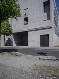 a man is riding a motorcycle in front of a building with a tree growing outside the building