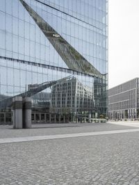 there is a large mirror on the side of this building with a small bench in the foreground