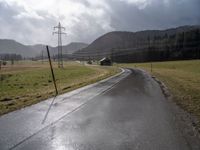 a country road lined with utility lines and power lines as a backdrop of mountains is shown on the horizon