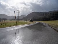 a country road lined with utility lines and power lines as a backdrop of mountains is shown on the horizon