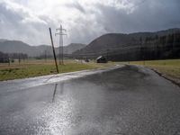 a country road lined with utility lines and power lines as a backdrop of mountains is shown on the horizon