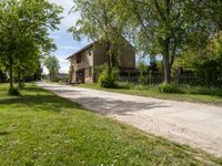 an image of an old country road through the country side of the country side, with buildings in the background