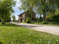 an image of an old country road through the country side of the country side, with buildings in the background