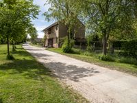 an image of an old country road through the country side of the country side, with buildings in the background