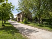 an image of an old country road through the country side of the country side, with buildings in the background