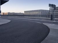 the building is made of concrete blocks next to a curved road in the middle of a deserted street