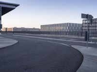 the building is made of concrete blocks next to a curved road in the middle of a deserted street