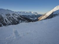 a person standing on the snow near mountains while ski touring down a slope's