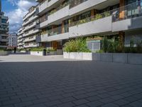 the buildings are white and grey with balconies in them and there is also plants in the balcony