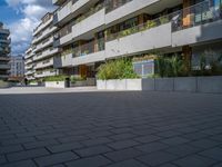 the buildings are white and grey with balconies in them and there is also plants in the balcony