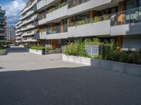 the buildings are white and grey with balconies in them and there is also plants in the balcony