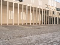 a person on a bike passing by a building that has columns on it with many doors