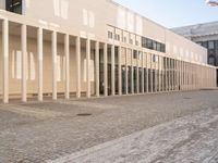 a person on a bike passing by a building that has columns on it with many doors