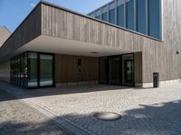 an empty courtyard and two large buildings with glass doors and concrete flooring is seen