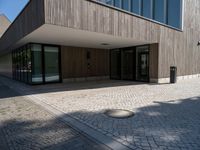 an empty courtyard and two large buildings with glass doors and concrete flooring is seen