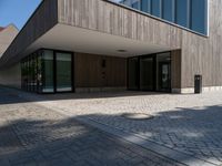 an empty courtyard and two large buildings with glass doors and concrete flooring is seen