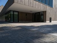 an empty courtyard and two large buildings with glass doors and concrete flooring is seen