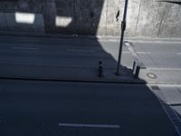 an empty street surrounded by a concrete wall with a streetlight pole and no street in sight