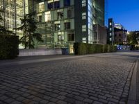 an empty square next to buildings at night, with a blue sky above the street