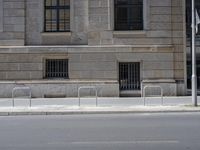 there is a street lined with stone barriers next to a building and there are no bikes or people