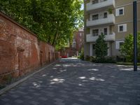 a paved brick street with red trash bins sitting in the middle and trees near to it