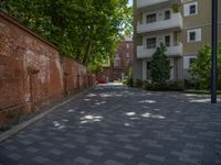 a paved brick street with red trash bins sitting in the middle and trees near to it