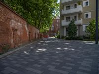 a paved brick street with red trash bins sitting in the middle and trees near to it