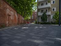 a paved brick street with red trash bins sitting in the middle and trees near to it