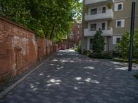 a paved brick street with red trash bins sitting in the middle and trees near to it