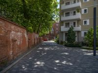 a paved brick street with red trash bins sitting in the middle and trees near to it