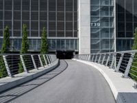 a small concrete walkway near a large glass building with a metal frame over it in front